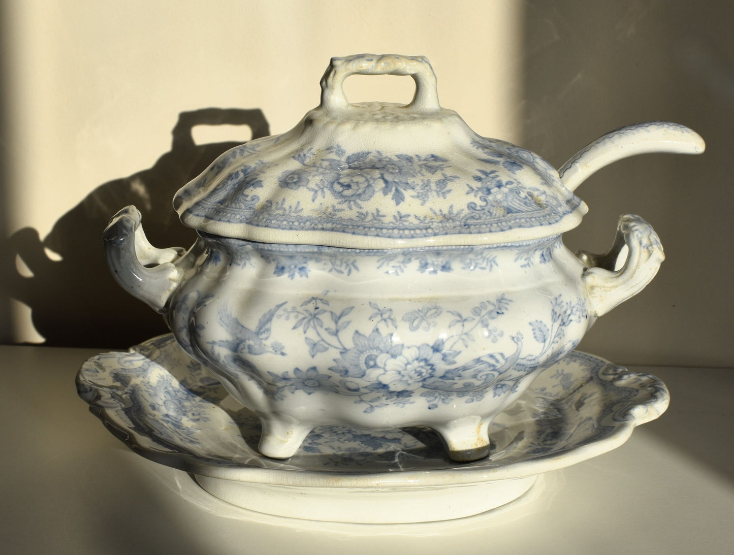 A lidded tureen, with ladle handle and on a stand, are all decorated with blue and white Asiatic Pheasant pattern, which includes birds and flowers.