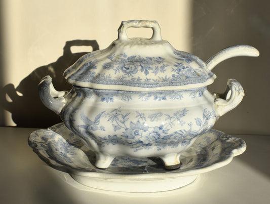 A lidded tureen, with ladle handle and on a stand, are all decorated with blue and white Asiatic Pheasant pattern, which includes birds and flowers.