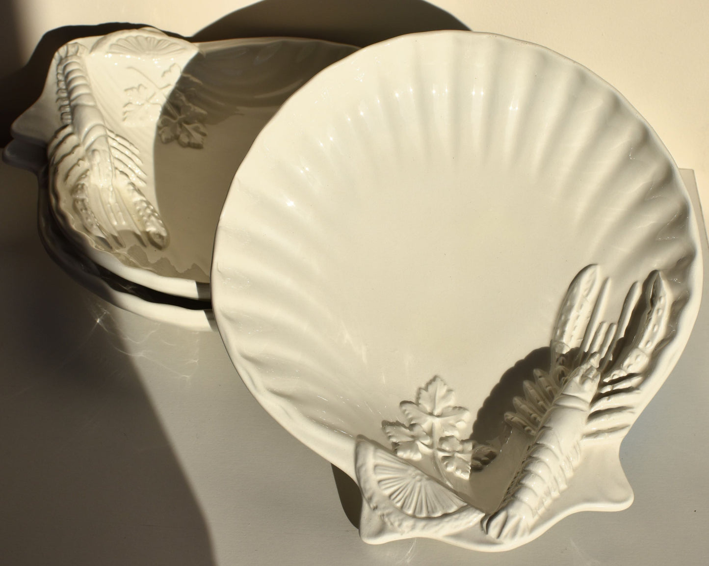 White dishes are decorated with lobsters, lemon slices and parsley leaves in relief