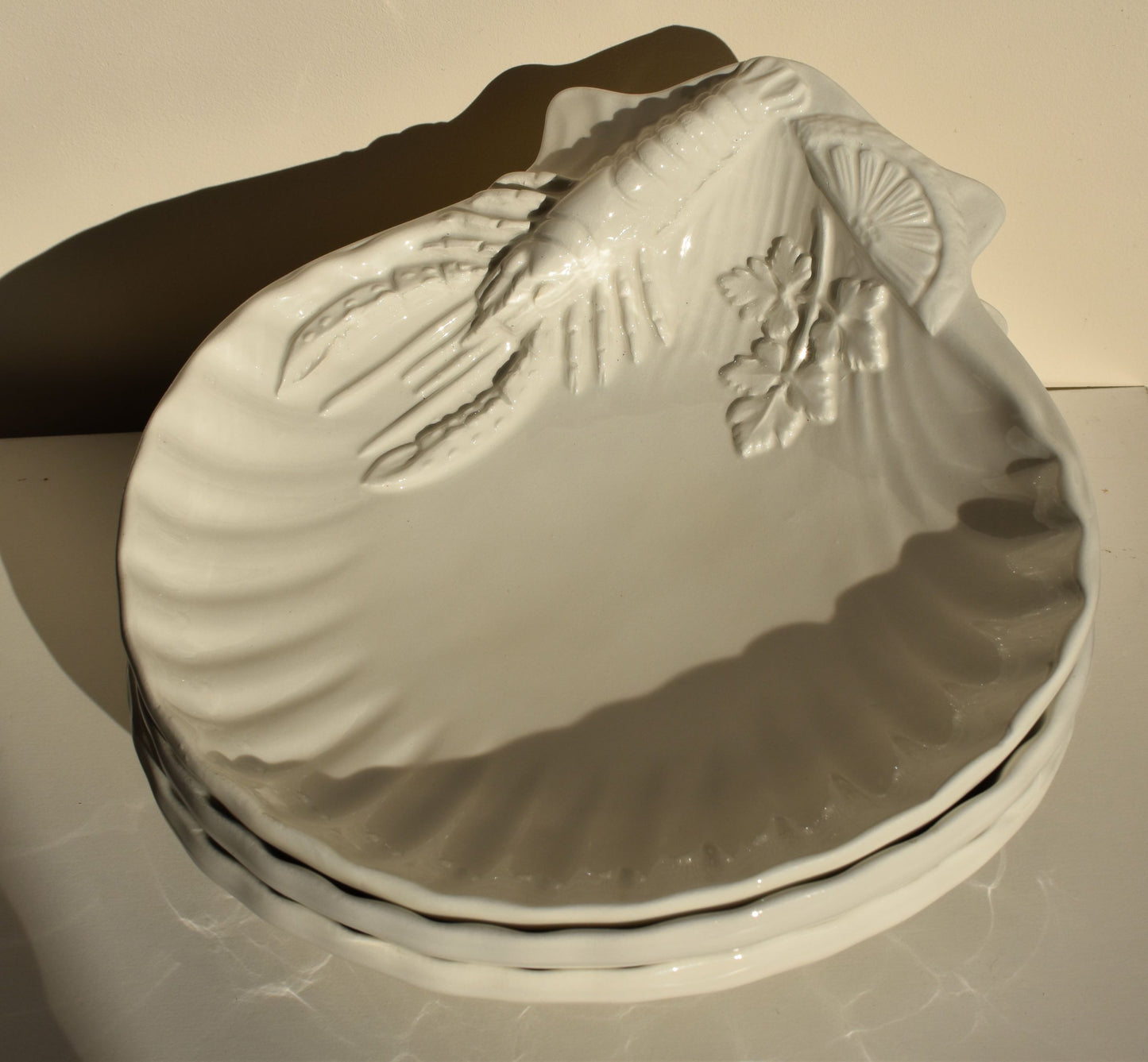 White dishes are decorated with lobsters, lemon slices and parsley leaves in relief