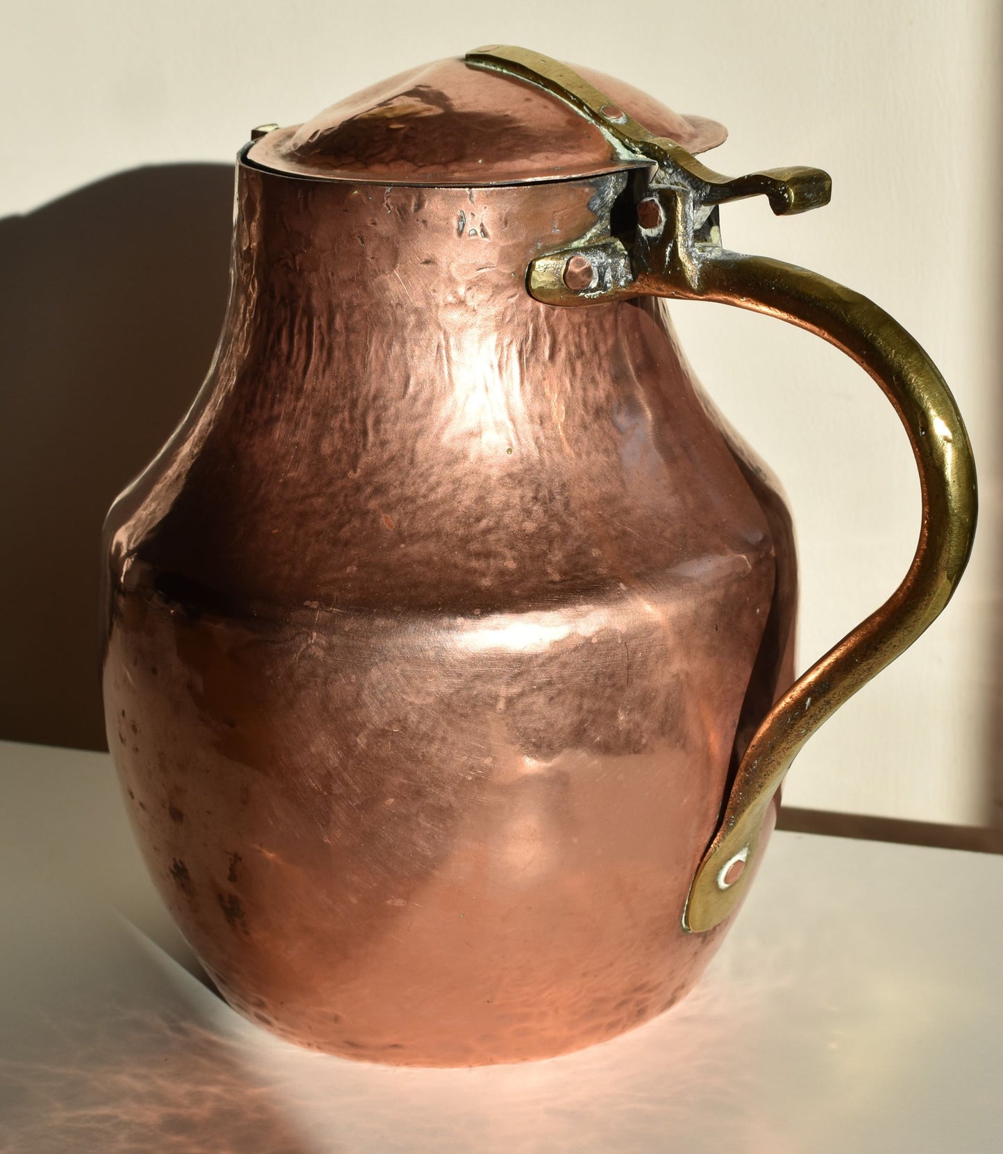 A large copper lidded jug, showing brass handle and hinge