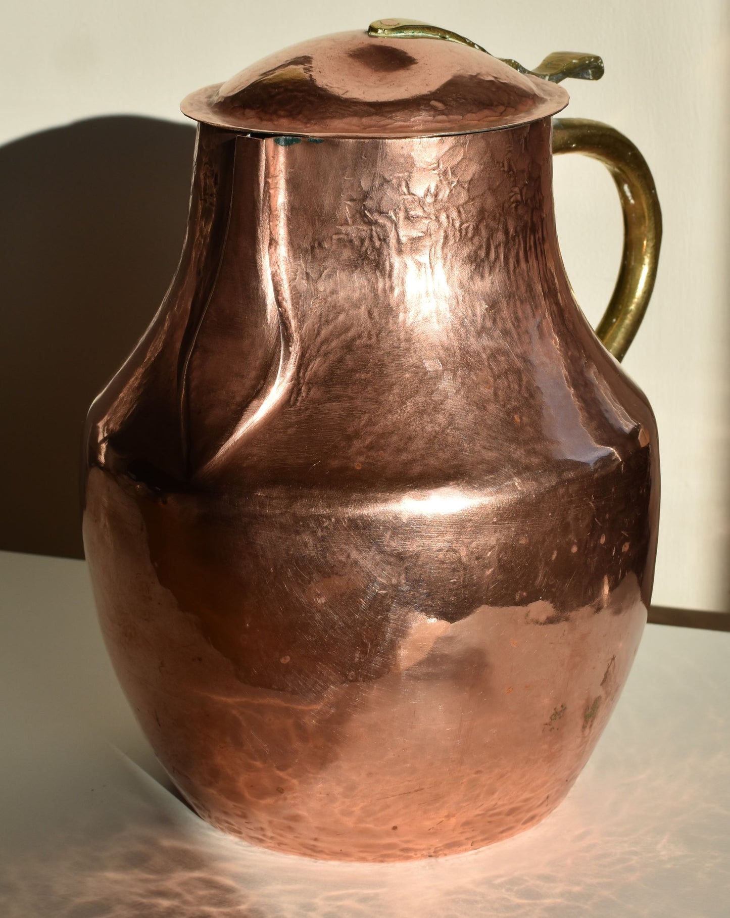 A large copper jug, showing copper lid and spout