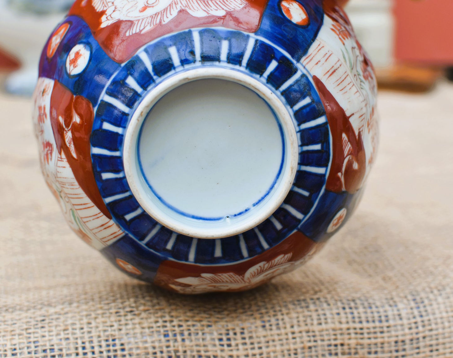 Decorative ceramic vase with red, blue, and white patterns on a textured surface.