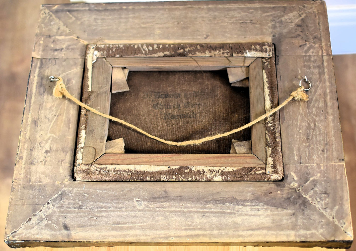 Back of the frame showing original oil canvas, wooden framing and hanging cord
