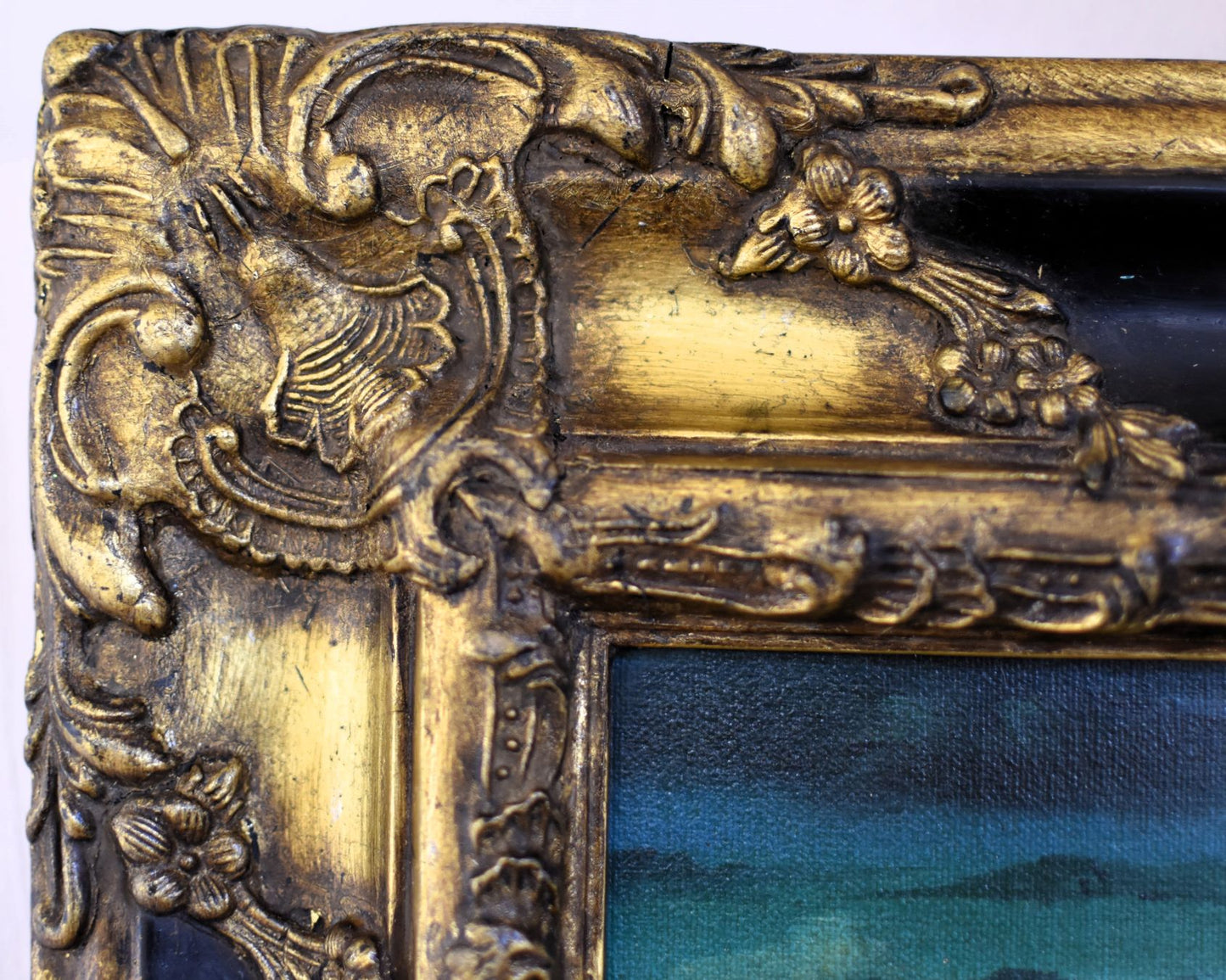 Close up of gold gilt frame showing scroll and flower details