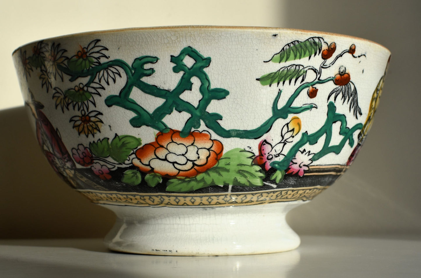The bowl is decorated with flowering plants in green, orange and pink