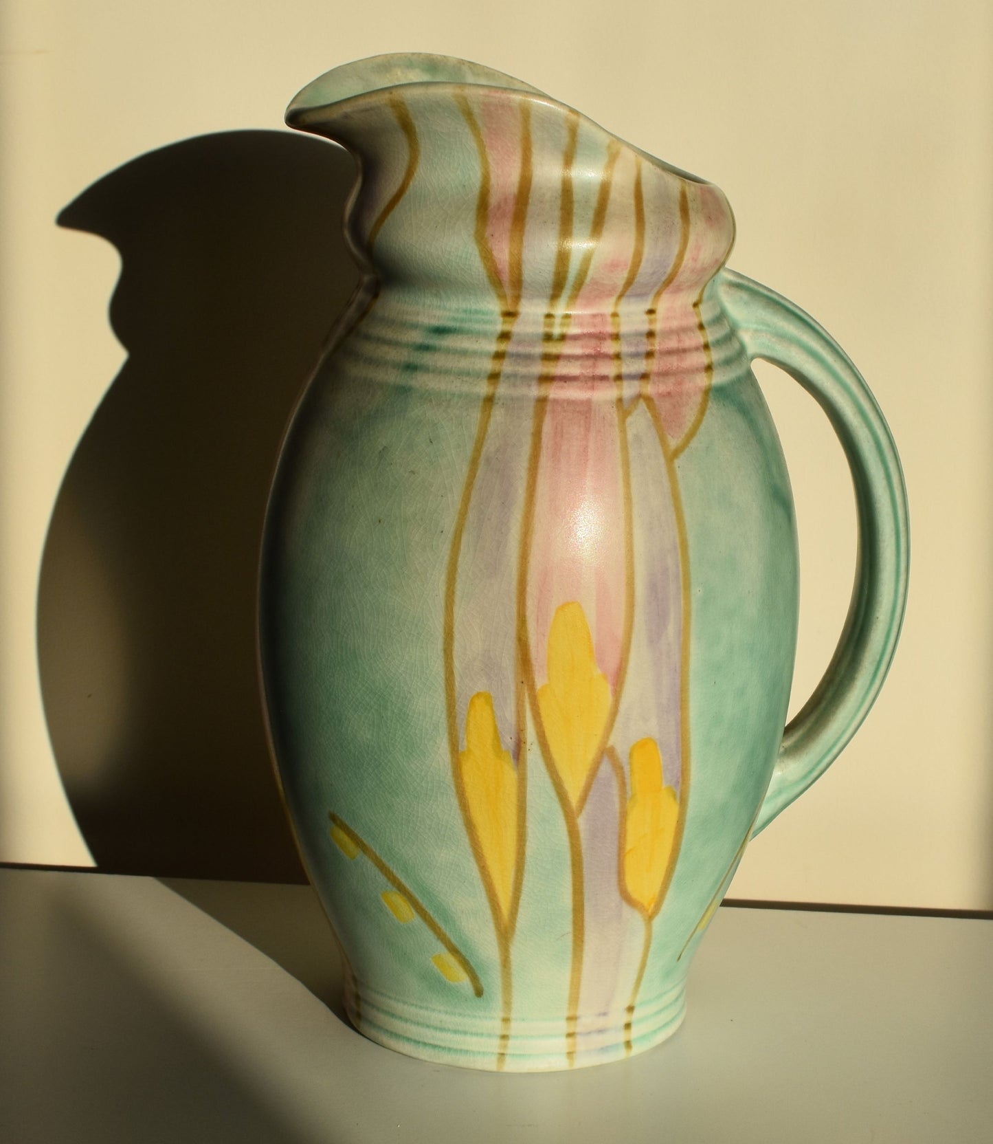 A green art deco jug is hand decorated with an abstract yellow, purple and pink floral