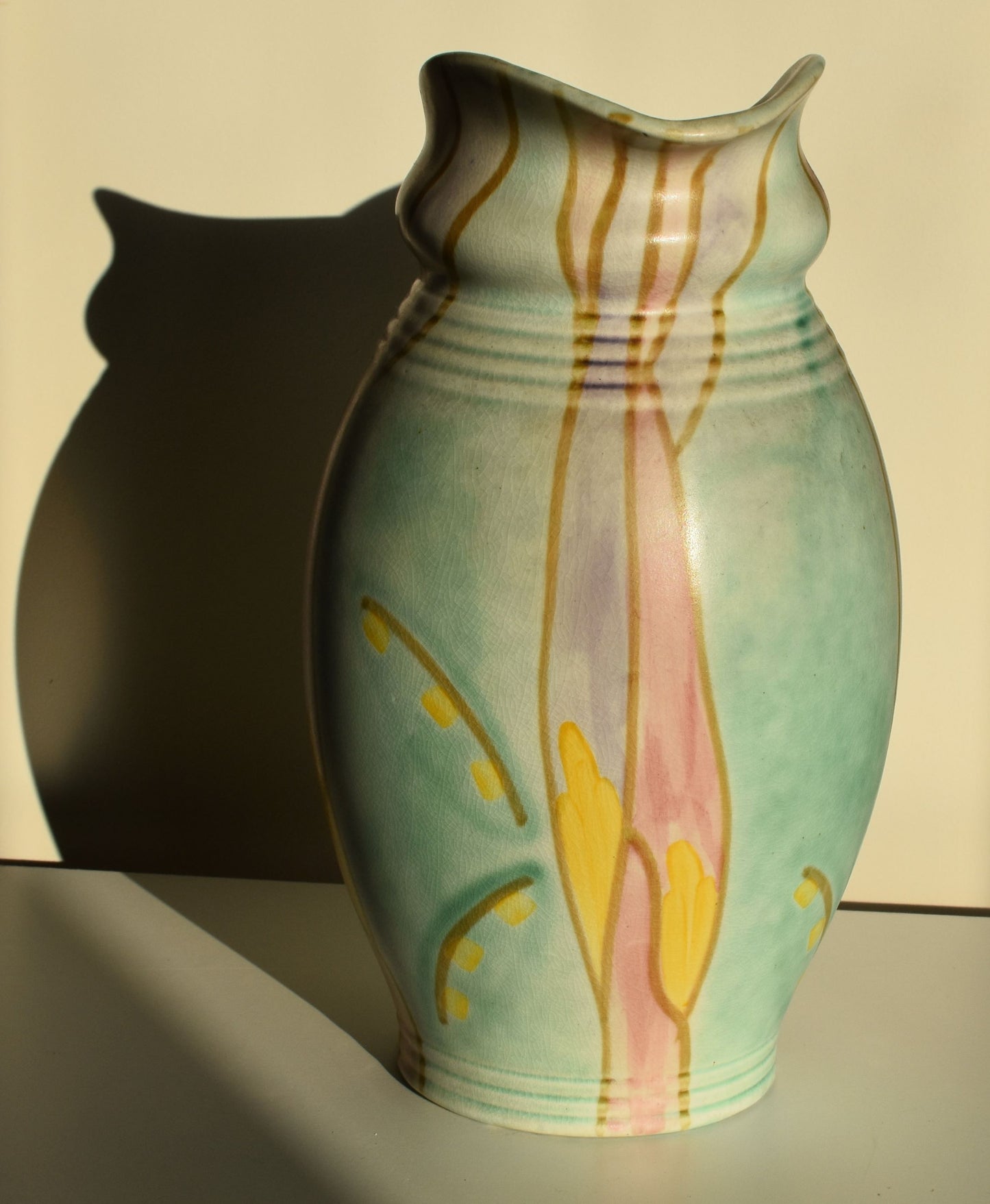 A green art deco jug is hand decorated with an abstract yellow, purple and pink floral