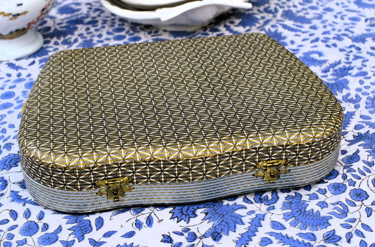 Decorative box with geometric pattern on a blue floral fabric background