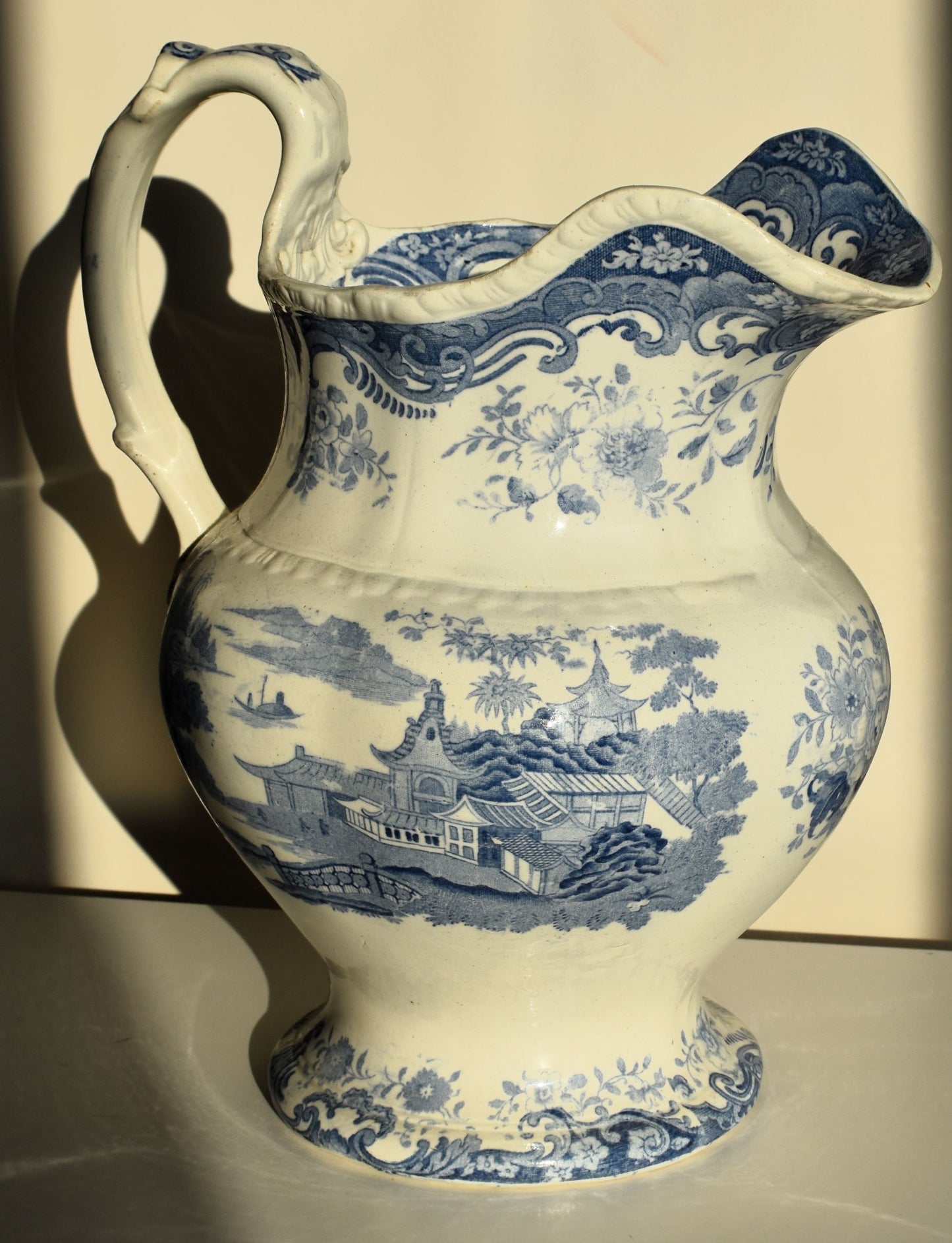A large victorian pitcher jug decorated with chinoiserie scenes and florals