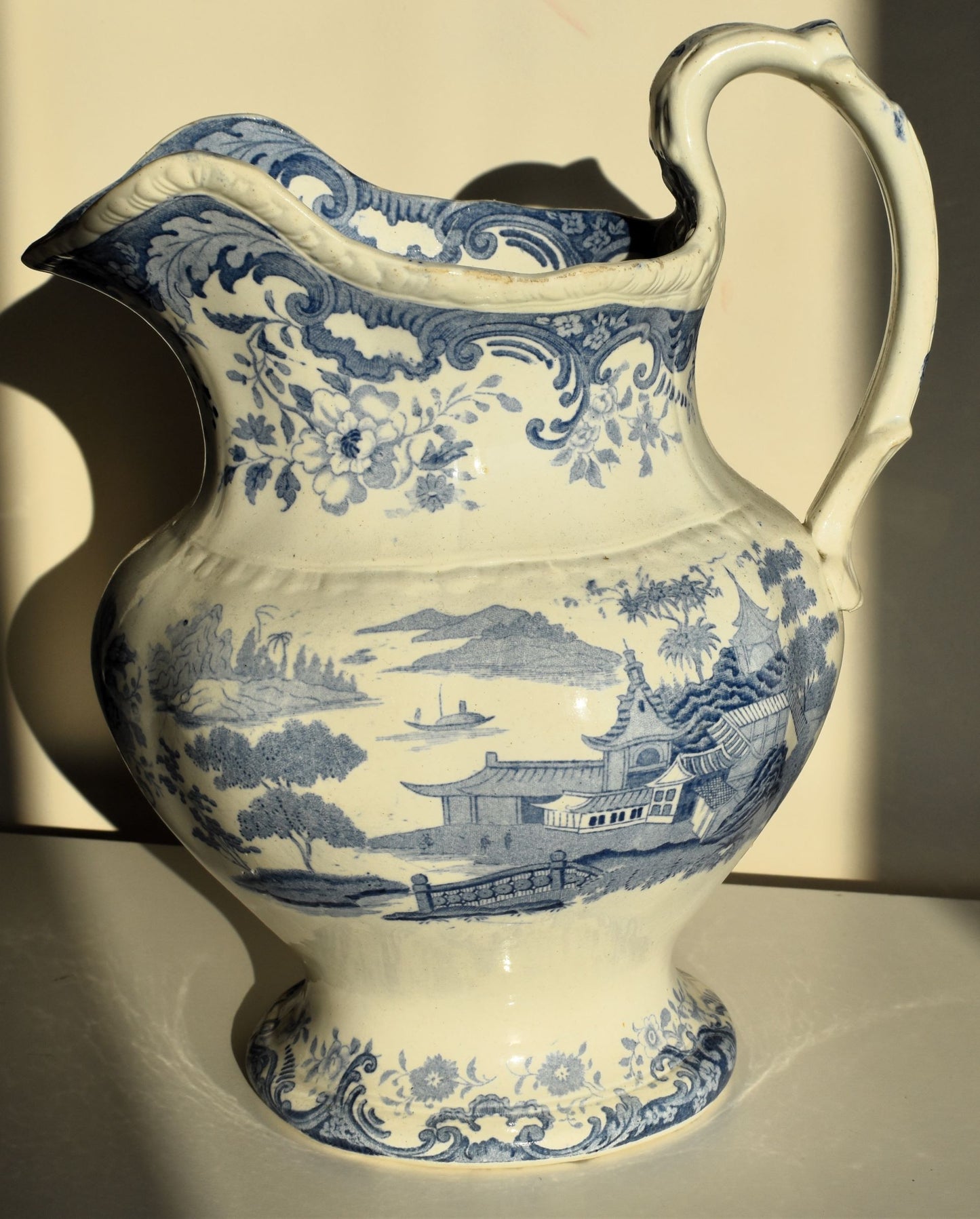 A large victorian pitcher jug decorated with chinoiserie scenes and florals