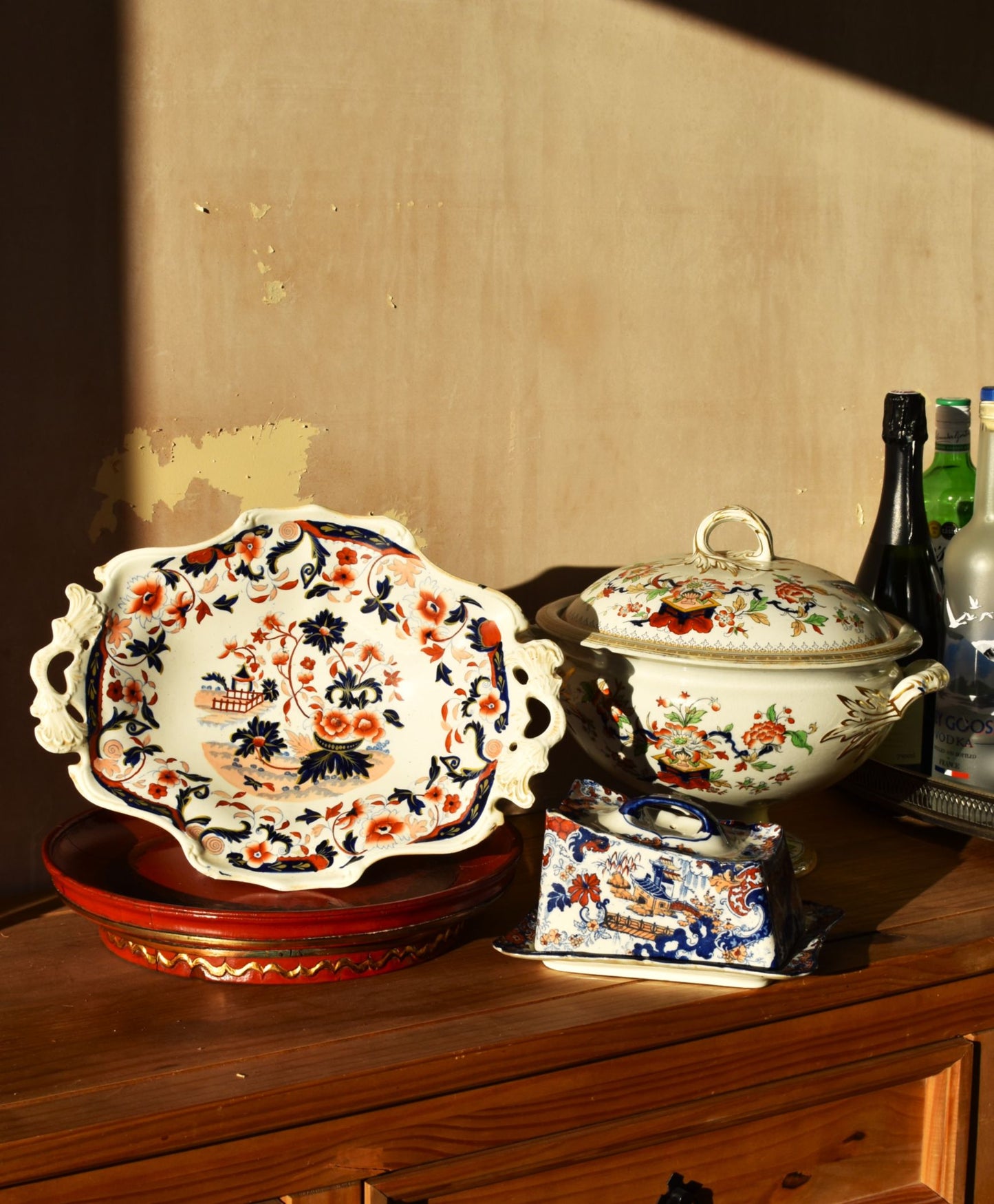 a group of white and floral ceramic plates and covered dishes on a wooden table