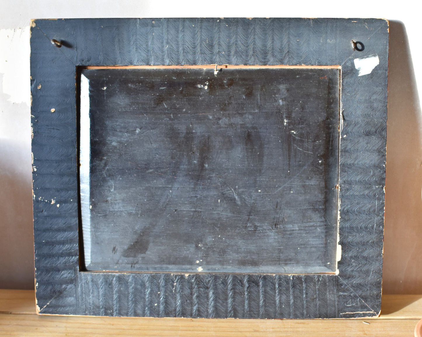 Backside of a wooden picture frame with visible wear and tear on a light background