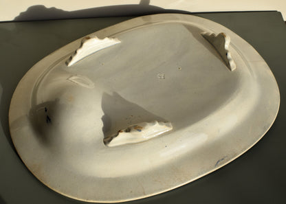 White china dish with a reflective surface on a dark background