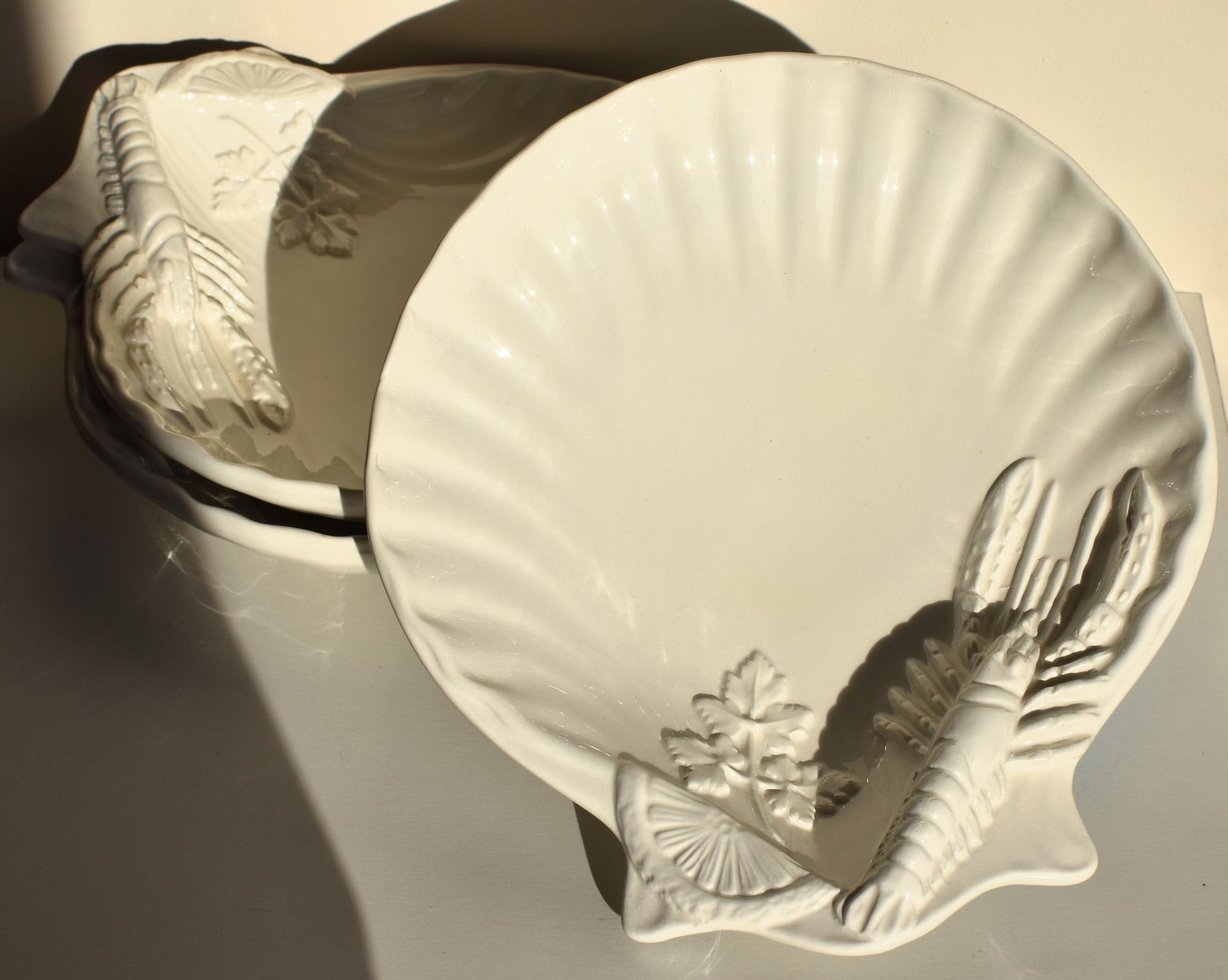 White dishes are decorated with lobsters, lemon slices and parsley leaves in relief