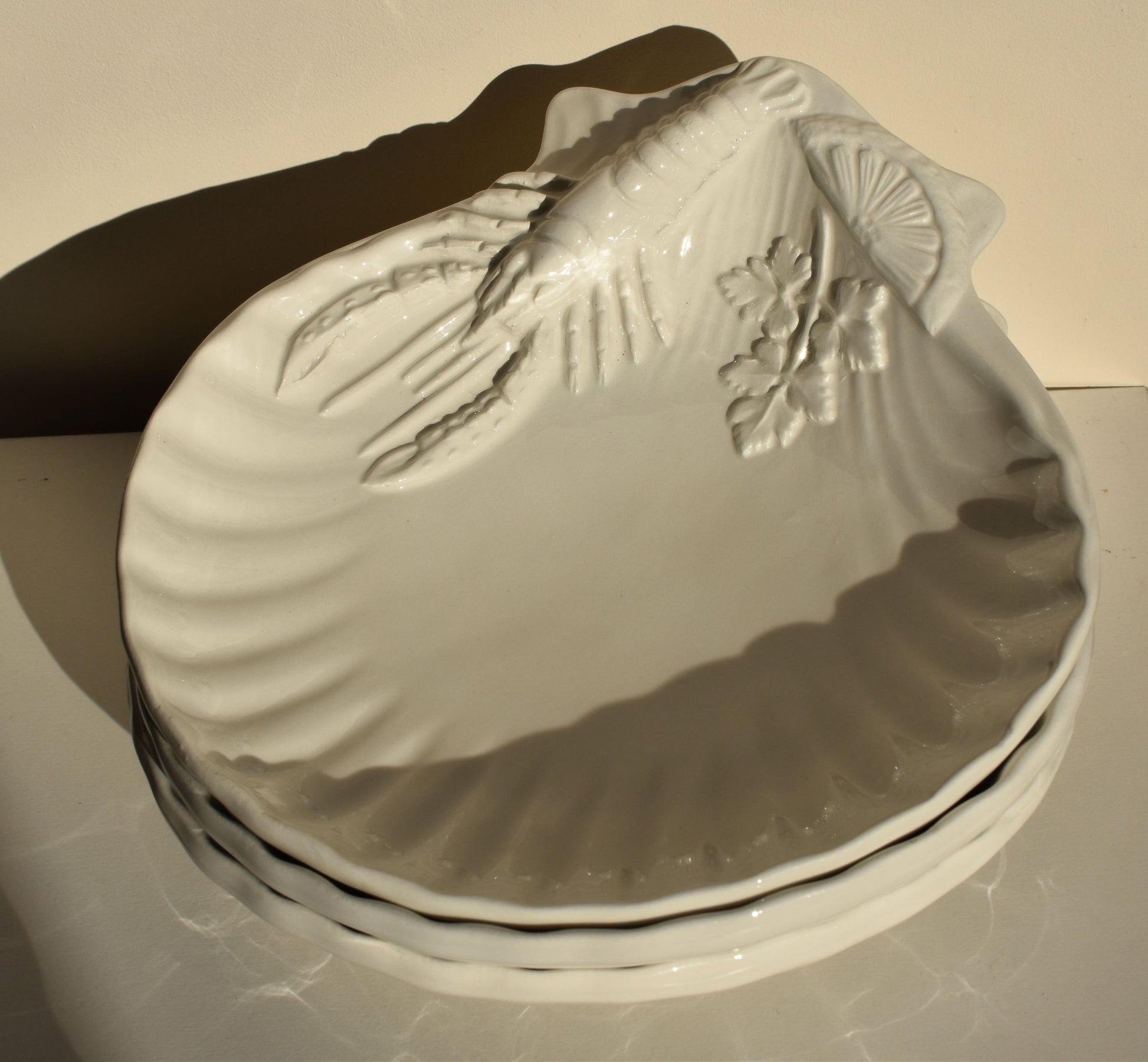 White dishes are decorated with lobsters, lemon slices and parsley leaves in relief