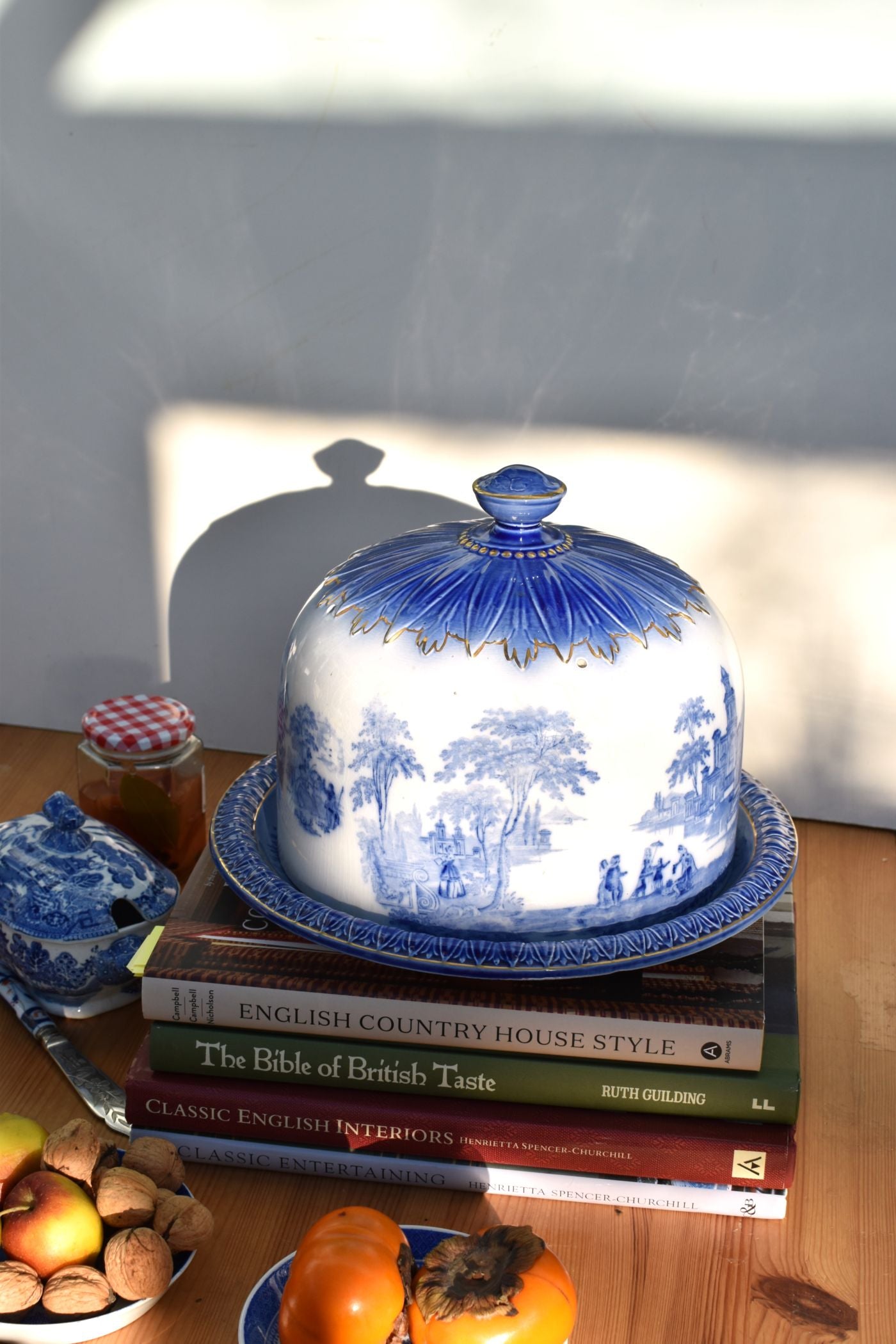 Blue and white ceramic cloche on a stack of books with a neutral background