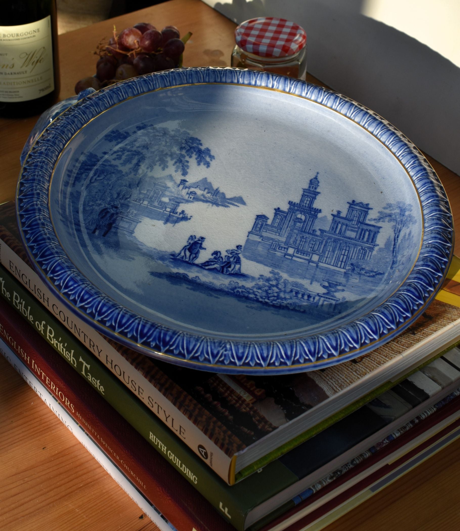 Blue decorative plate with a scenic design on top of books