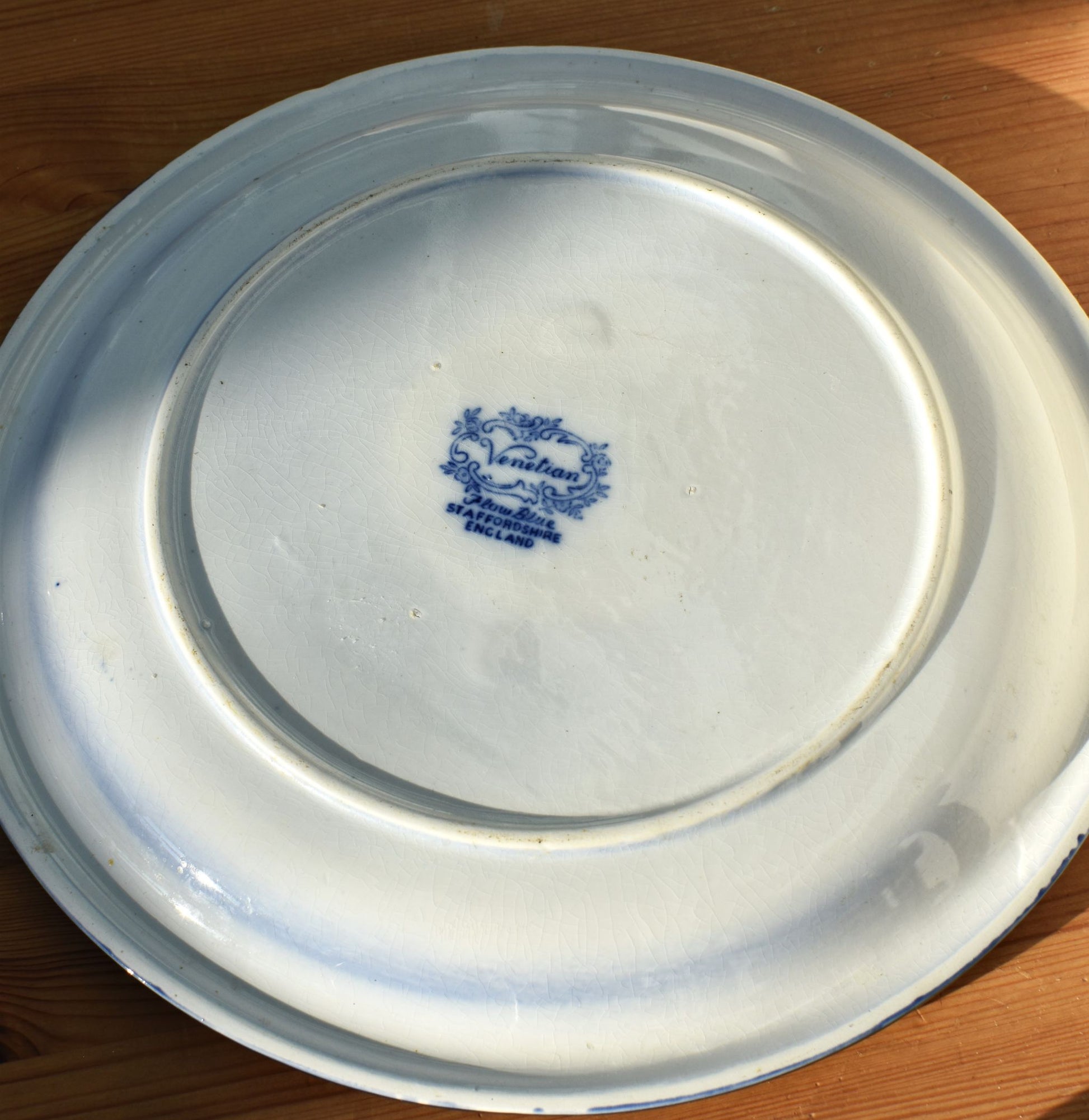 White ceramic plate with blue logo on a wooden surface