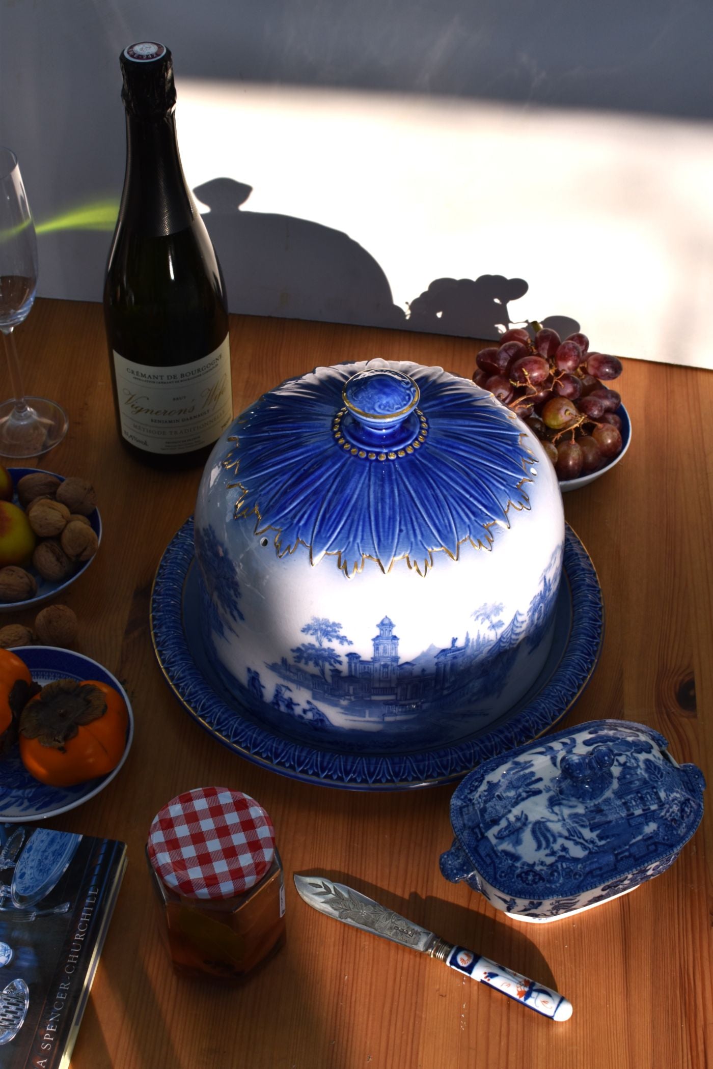 Table setting with a blue and white ceramic dish, bottle, and fruit on a wooden table.