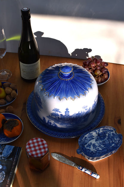 Table setting with a blue and white ceramic dish, bottle, and fruit on a wooden table.