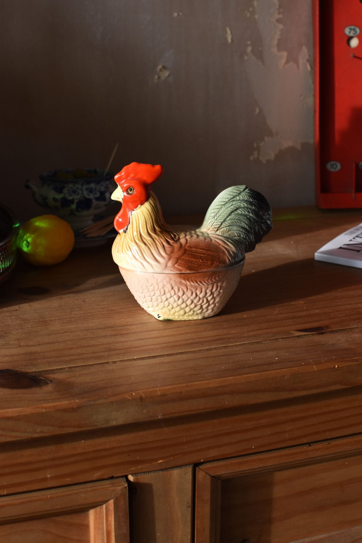 a covered dish in the shape of a cockerel on a wooden table