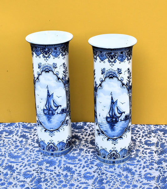 Two blue and white ceramic vases with ship design on a yellow background