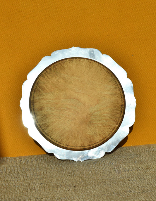 Wood and silver breadboard with a scalloped edge on an orange background