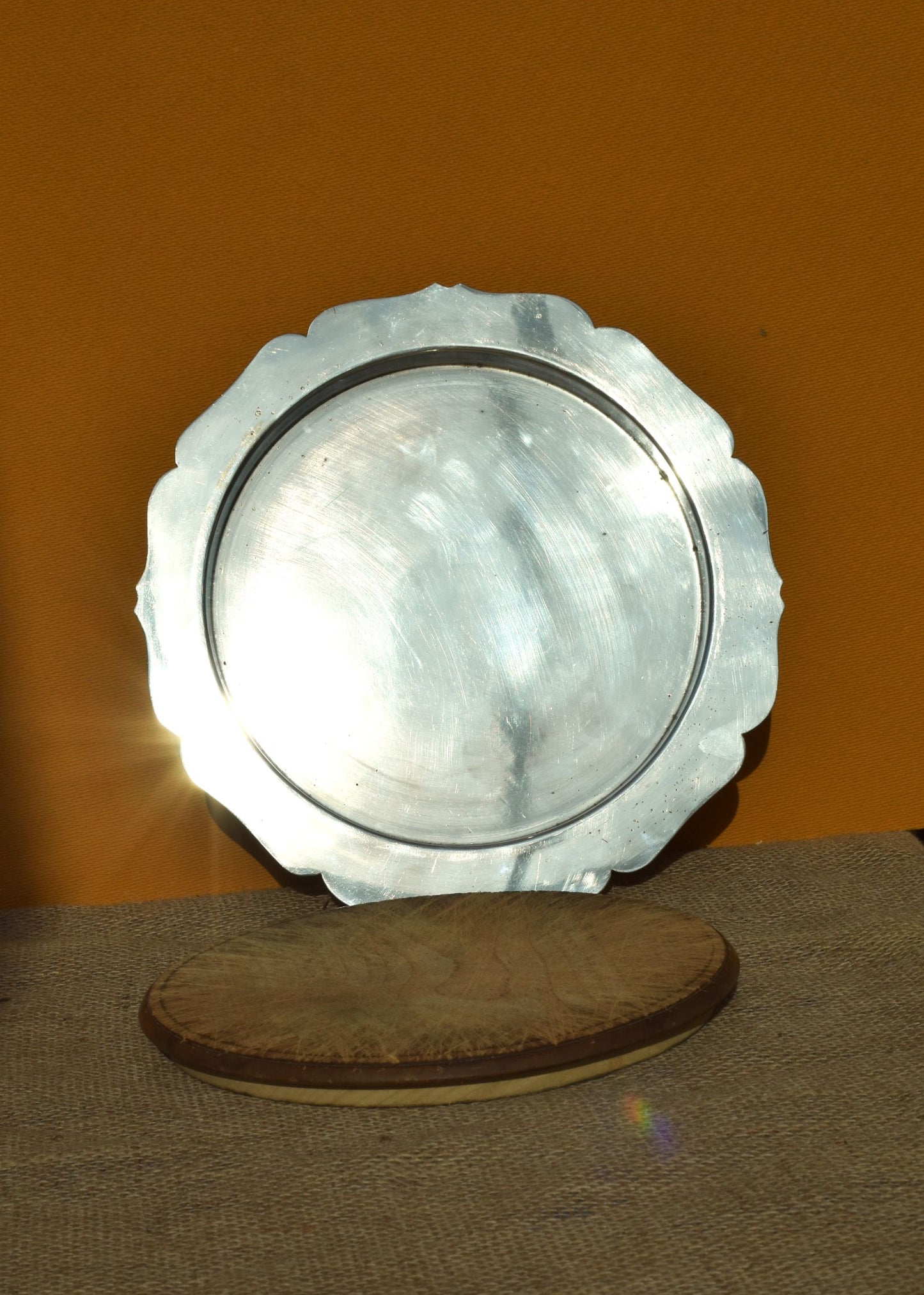 A silver plate with scalloped edges and wooden board