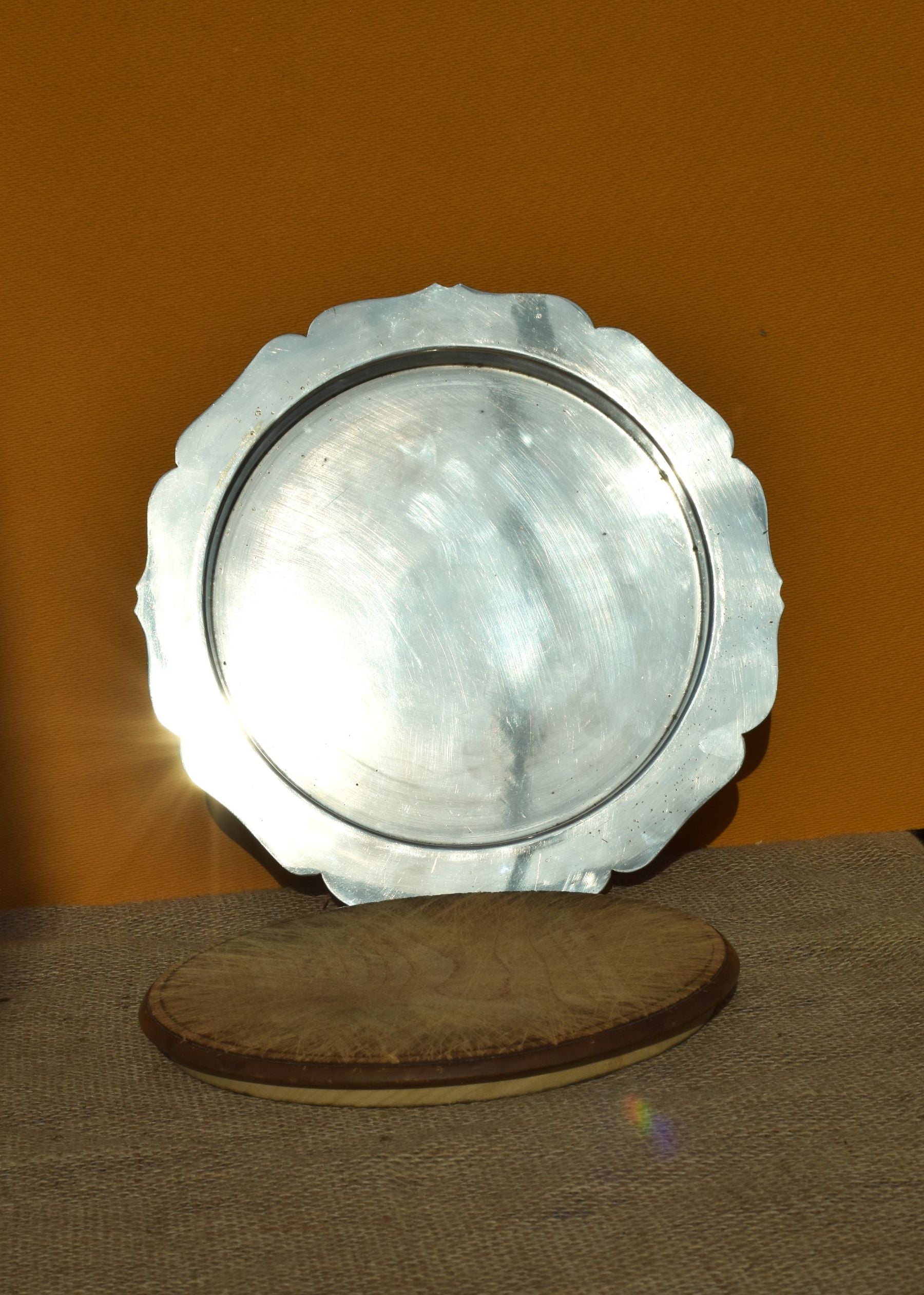 A silver plate with scalloped edges and wooden board