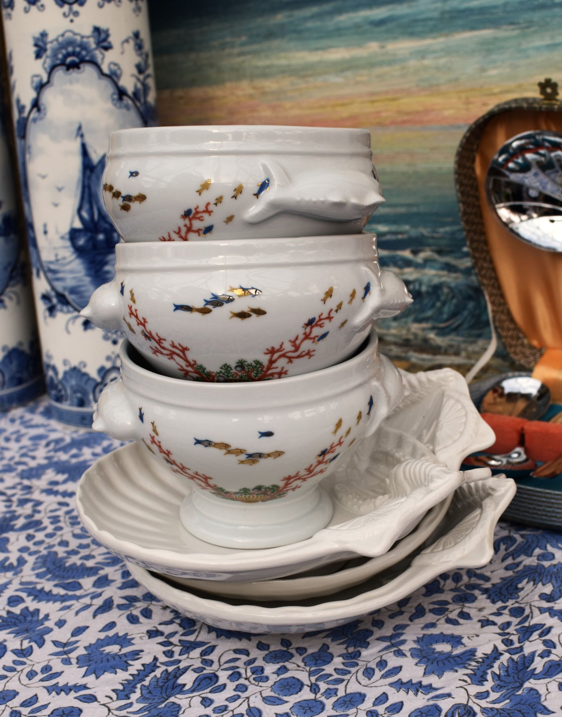 Stack of decorative white bowls with colorful patterns on a blue floral tablecloth.