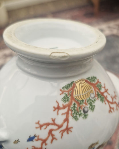 Decorative ceramic vase with shell and coral design on a blurred background