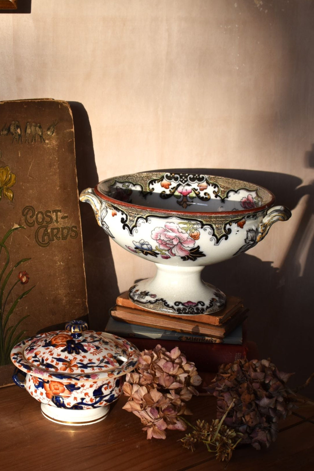 Decorative ceramic items on a wooden surface with a book titled 'Post Cards'.