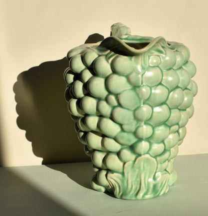 Green ceramic vase with textured surface on a plain background