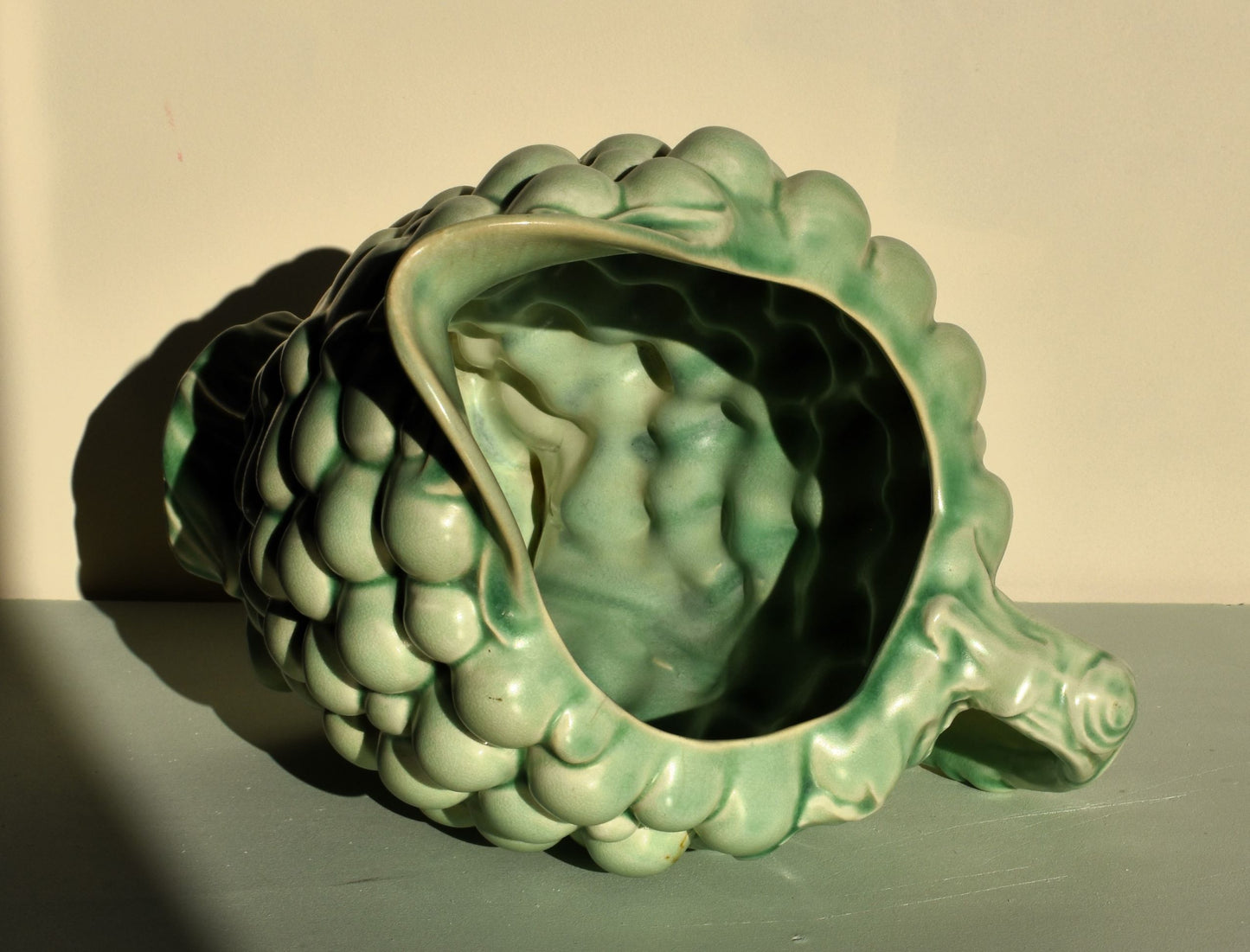 Green ceramic artichoke-shaped planter on a neutral background