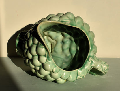 Green ceramic artichoke-shaped planter on a neutral background