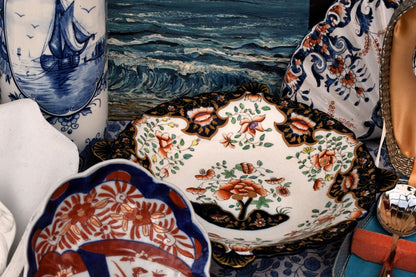 Collection of decorative items including shells, ceramic plates, and a painting of a seascape.