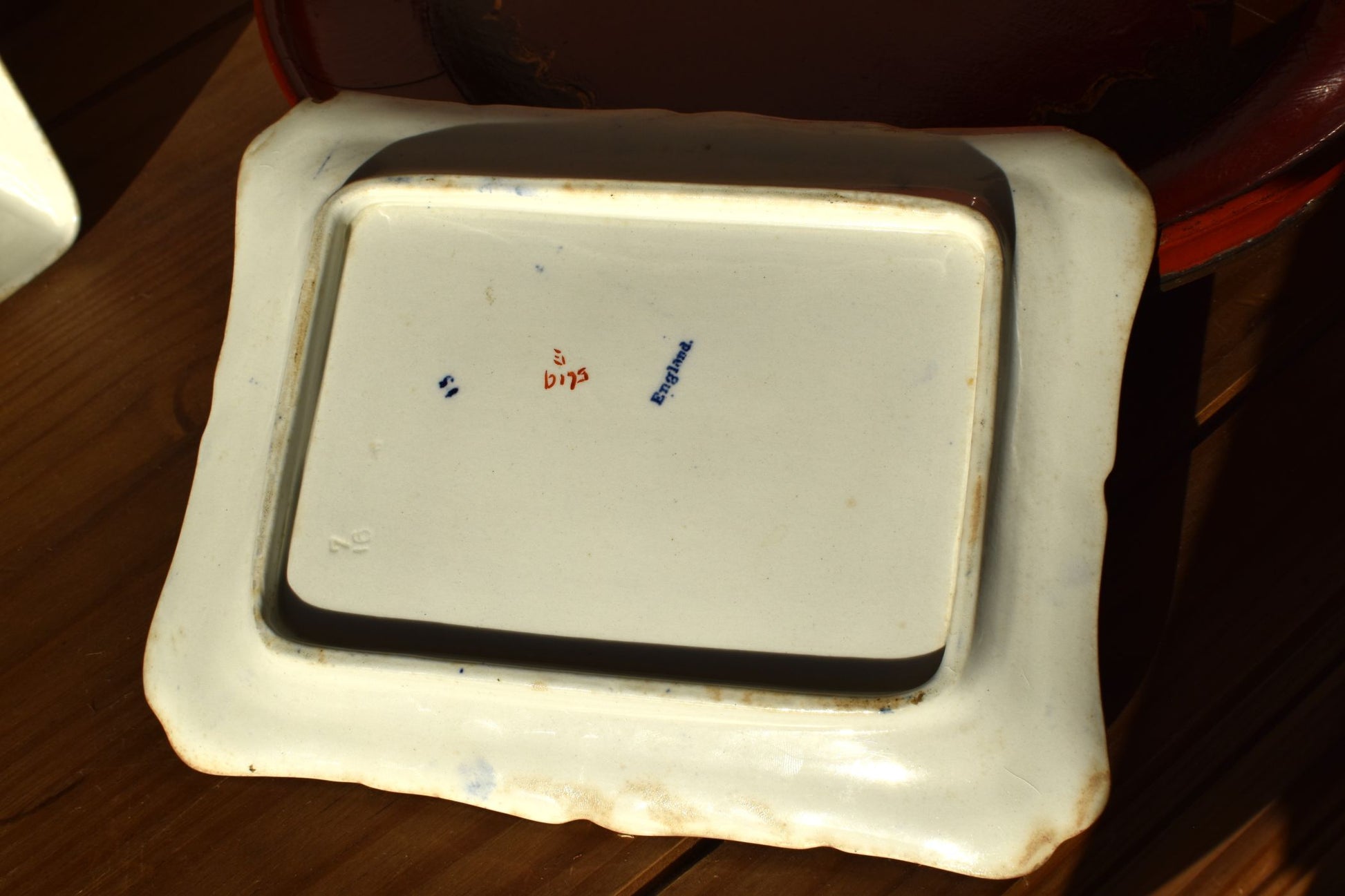 A white dish with the maker's mark England, on a wooden background