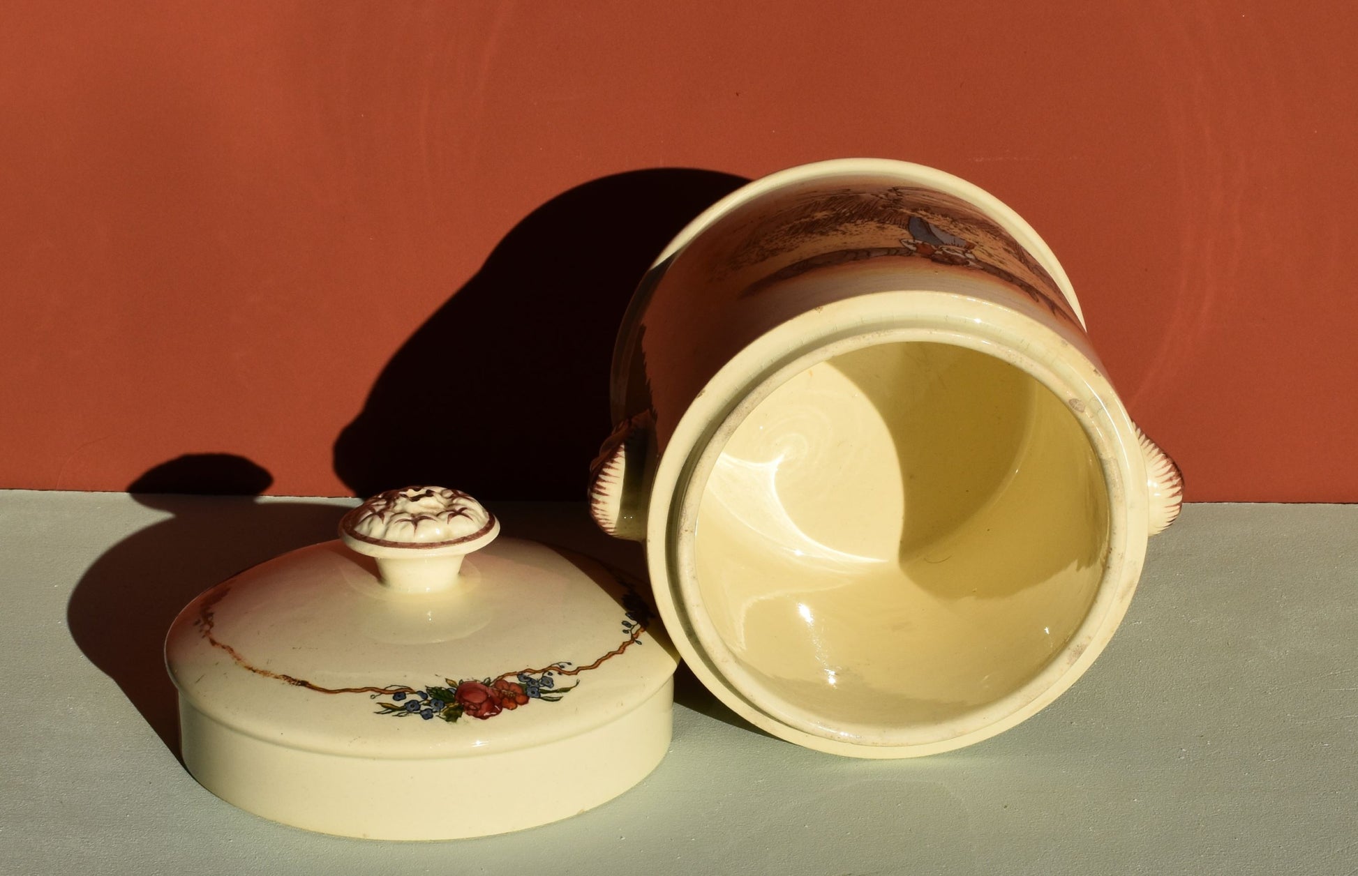 Ceramic jar with lid on a flat surface against a red background