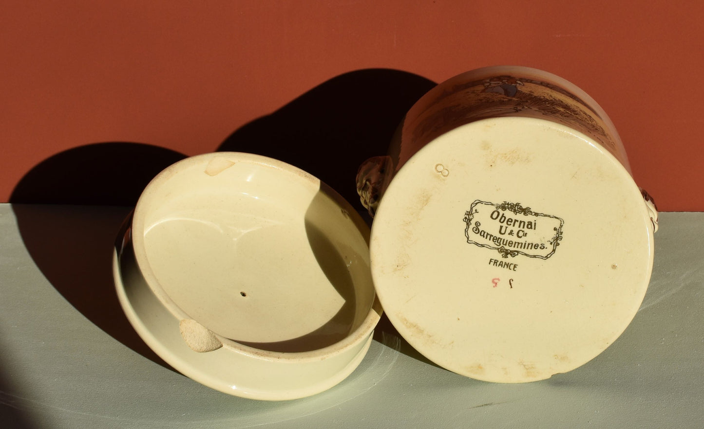 Ceramic jar with a lid on a green surface against a red background