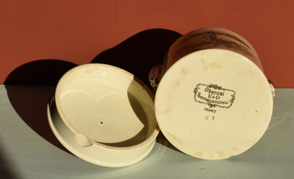 Ceramic jar with a lid on a green surface against a red background