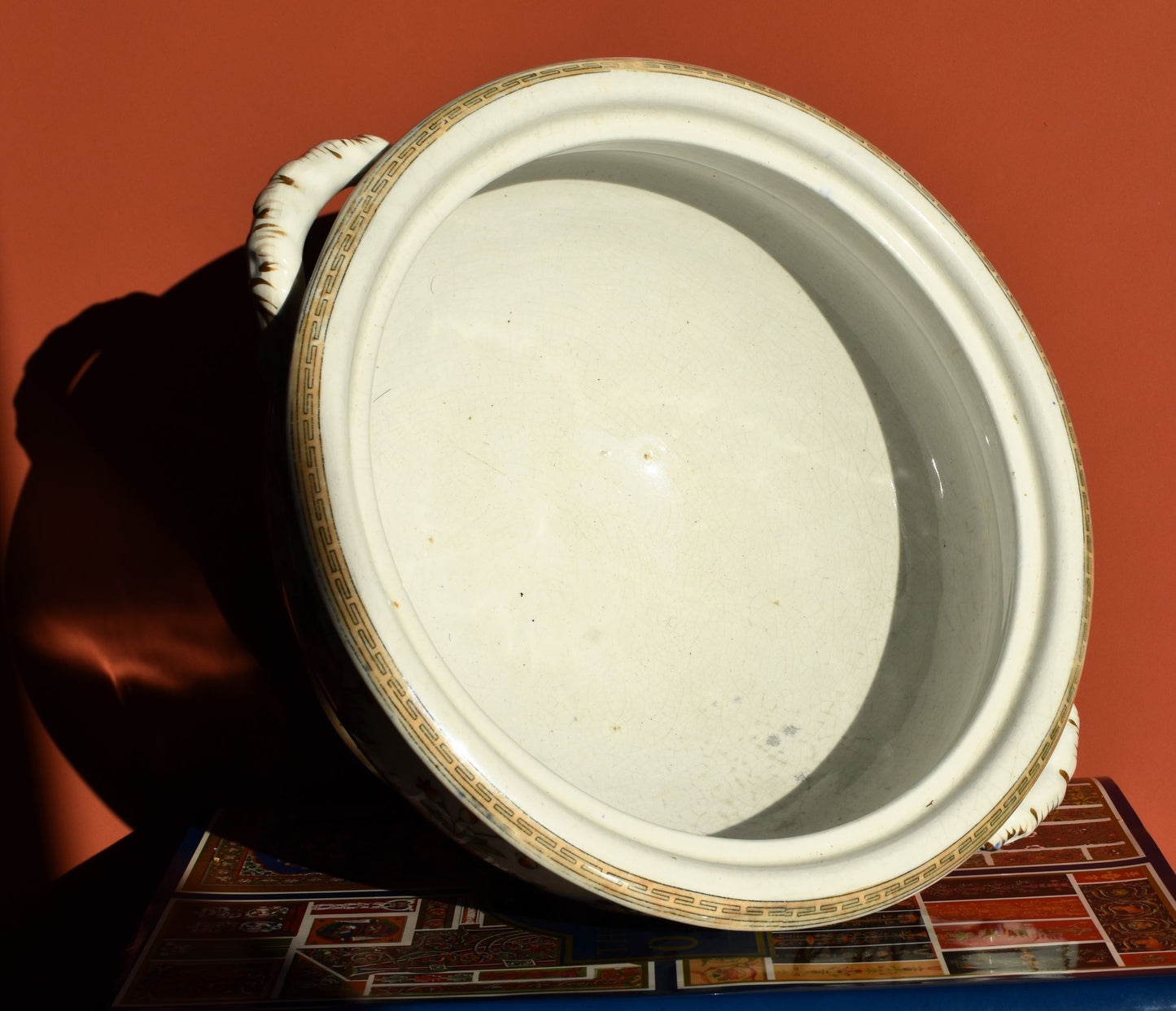 Close-up of a ceramic pot with a plain interior against a red background