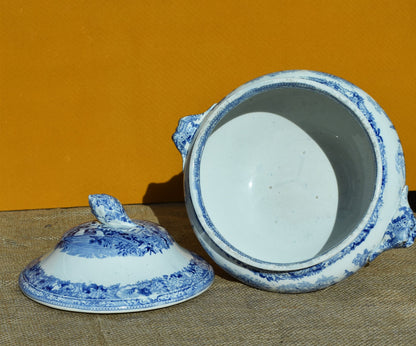 Blue and white ceramic dish with lid on a brown surface against an orange background