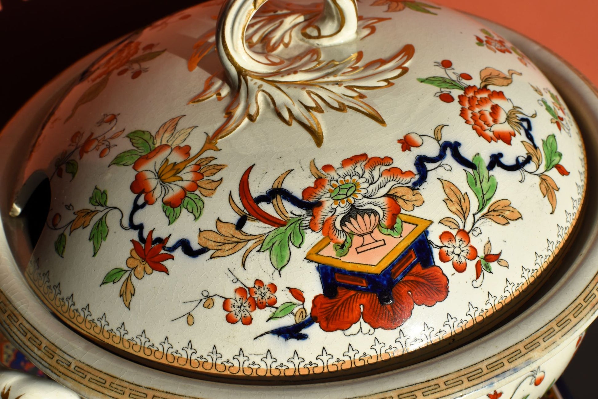 Decorative ceramic dish with floral patterns and a central emblem on a white background