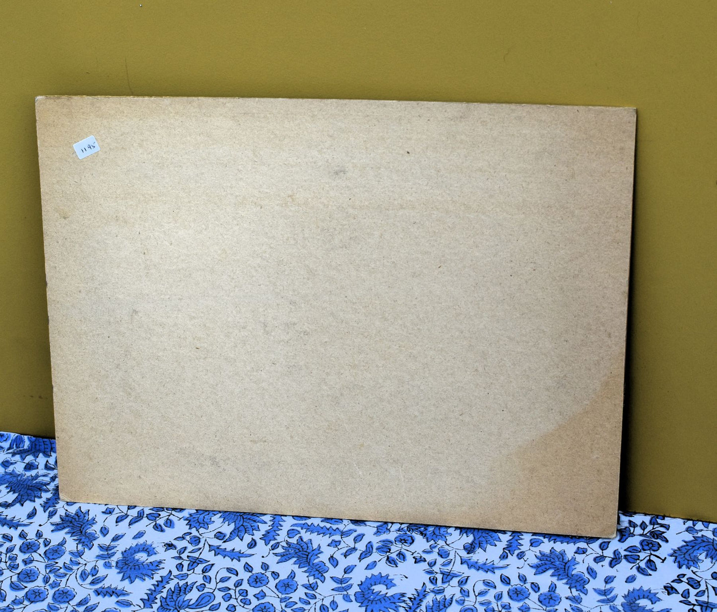 Large cardboard frame on a floral-patterned surface with a green background