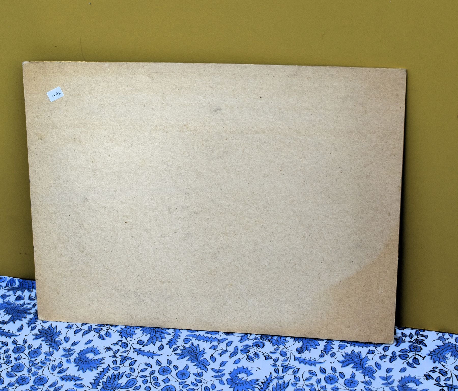 Large cardboard frame on a floral-patterned surface with a green background