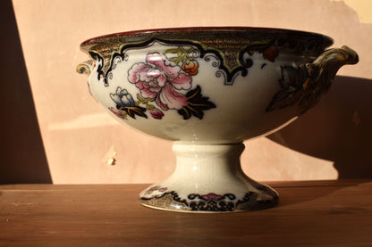 Art nouveau ceramic bowl with hand painted floral patterns on a wooden surface