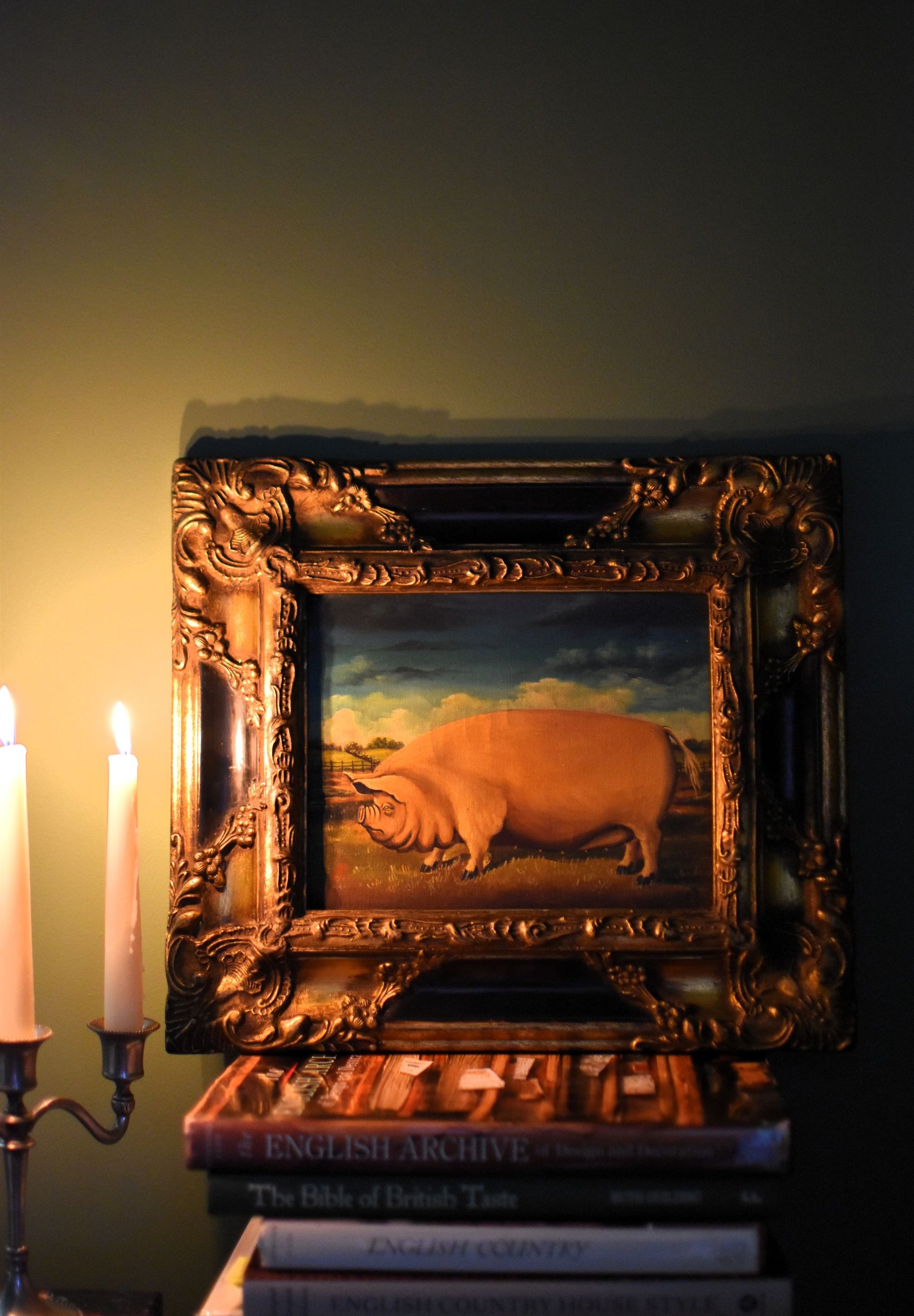 Oil painting of a large pink pig in a dark gold carved frame