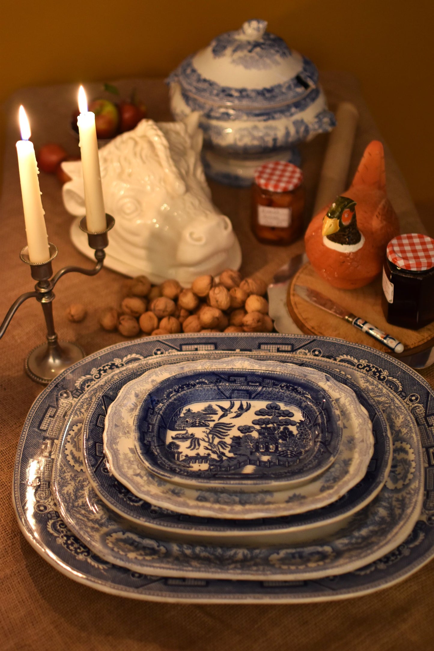 Stack of blue and white ceramic plates on a table with candles and other items.