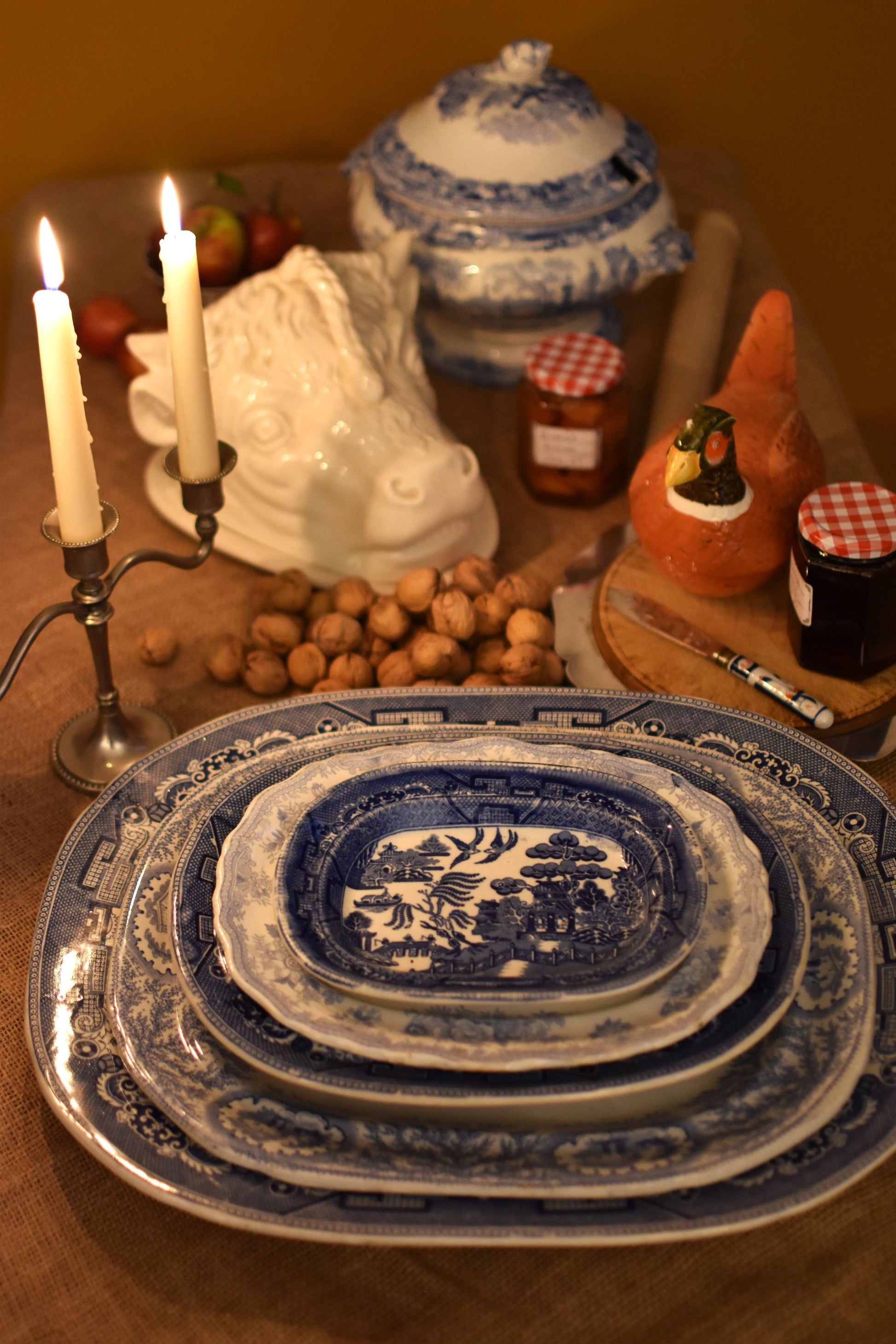 Stack of blue and white ceramic plates on a table with candles and other items.